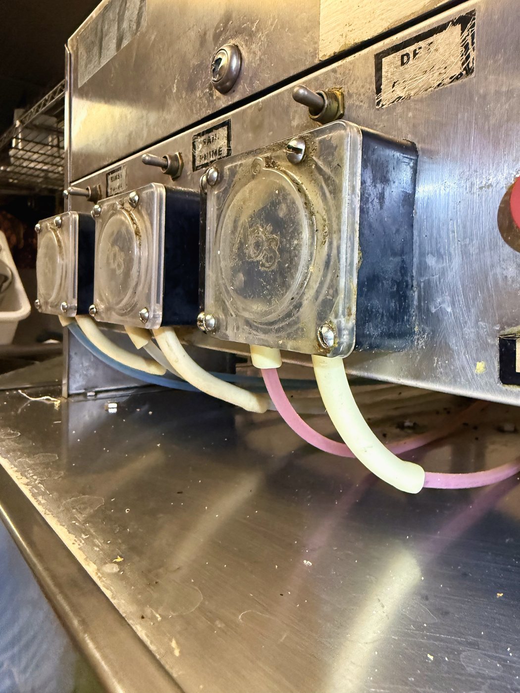 The three dispenser pumps — detergent, rinse and sanitiser. The soft tube inside each one is the wear part
