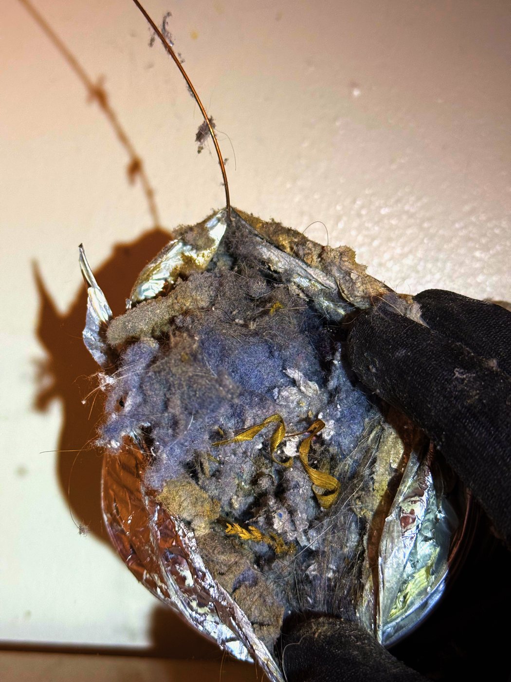 The old duct out and cut open. The blockage lifted out in one piece — a plug across the bore, not a dusting