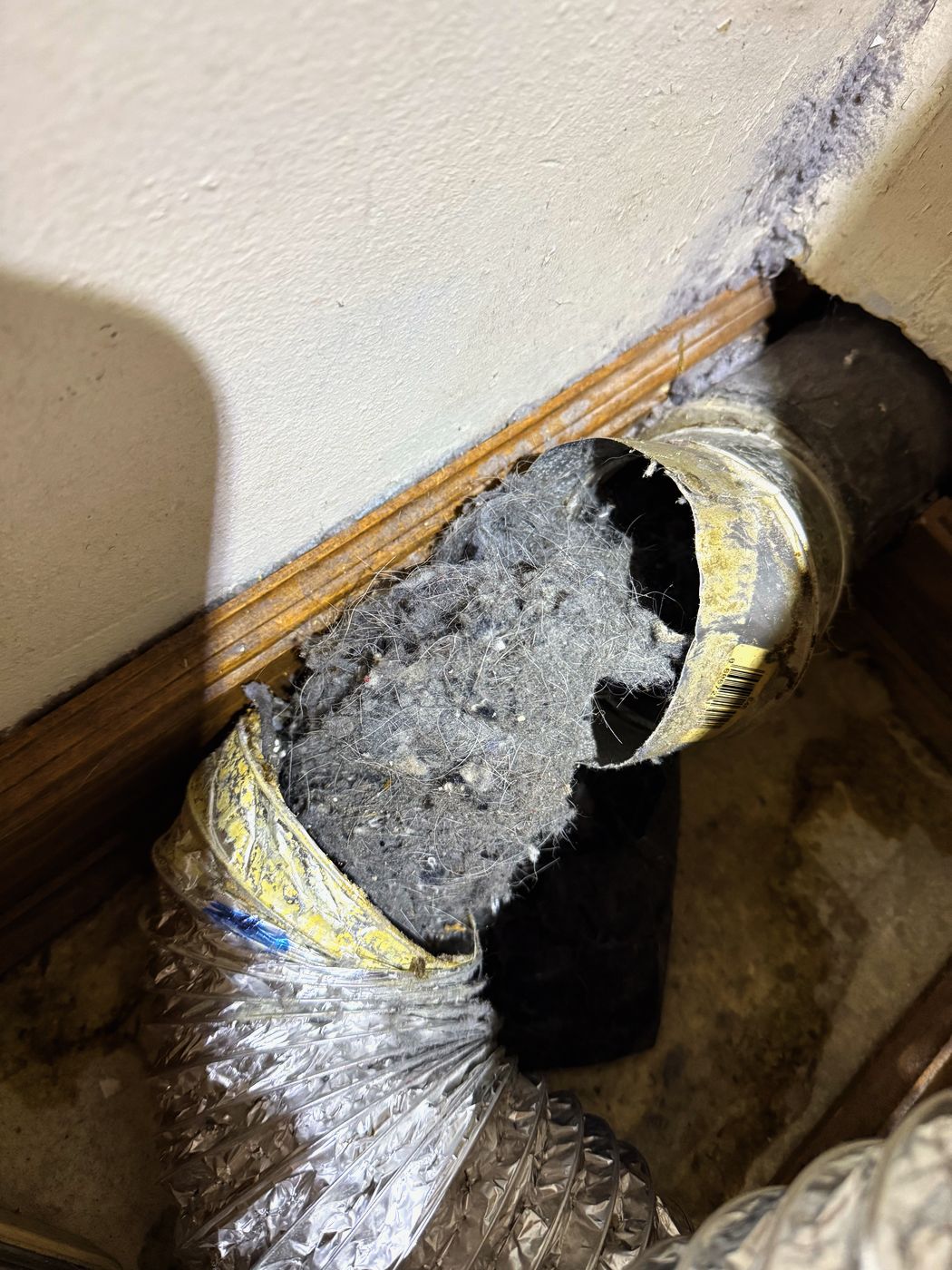 The transition duct behind the machine: split open along its length and packed solid. This one was replaced, not cleaned
