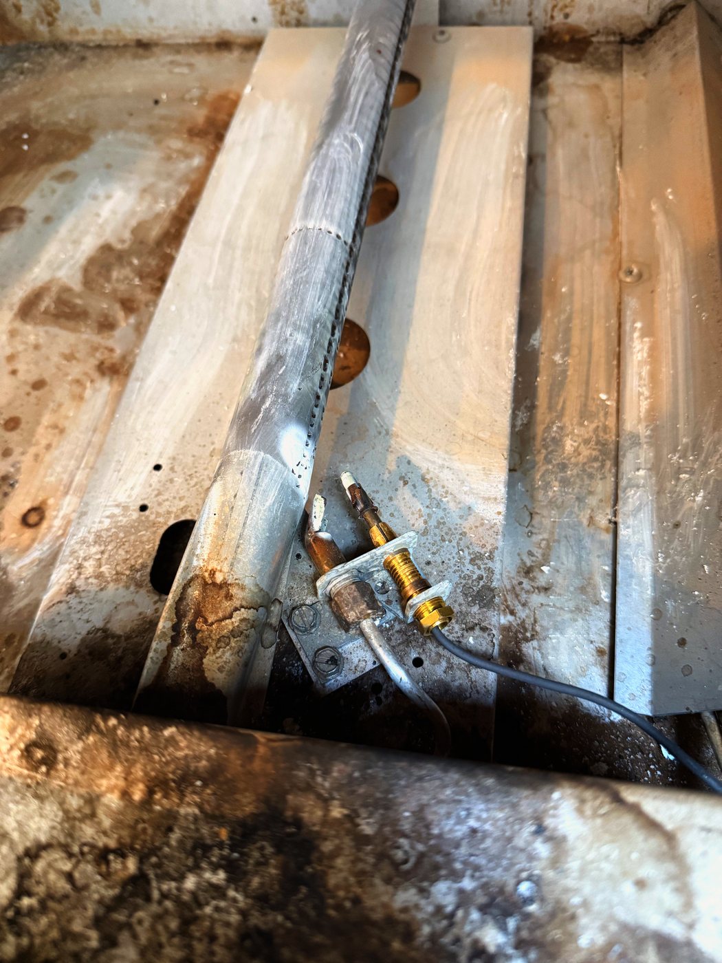 The assembly back in place on the oven floor, with the new thermocouple and its lead running to the valve