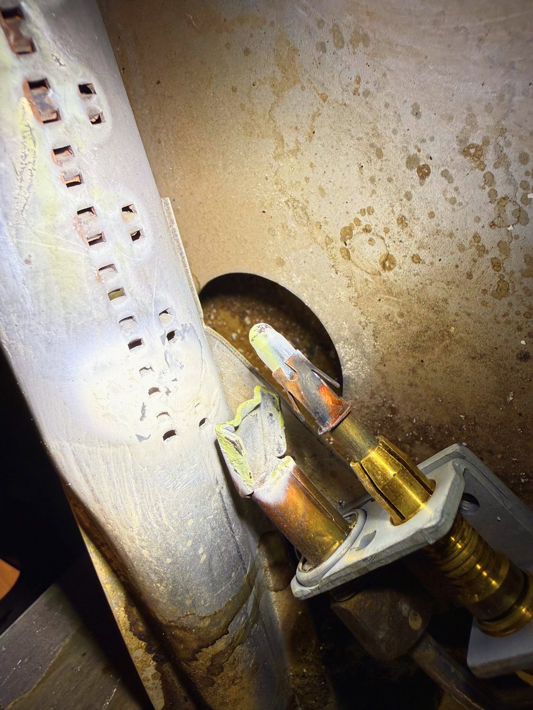 The pilot hood and the thermocouple probe beside the oven burner tube. The probe sits in the flame and makes its own current
