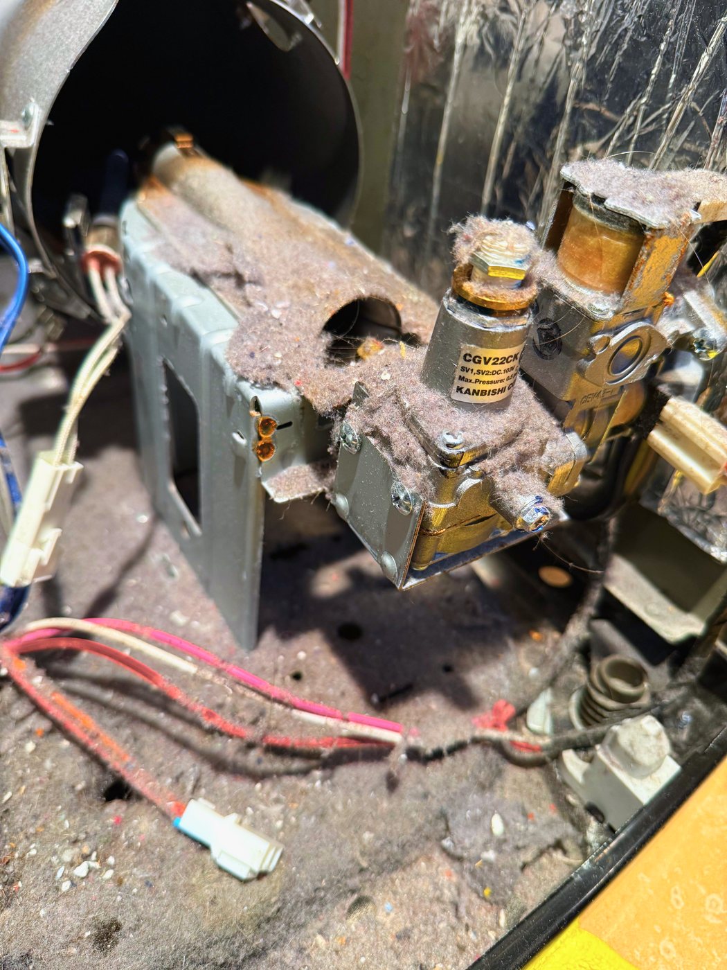 The burner housing and gas valve under years of felted lint. This is what a restricted vent duct leaves inside a machine