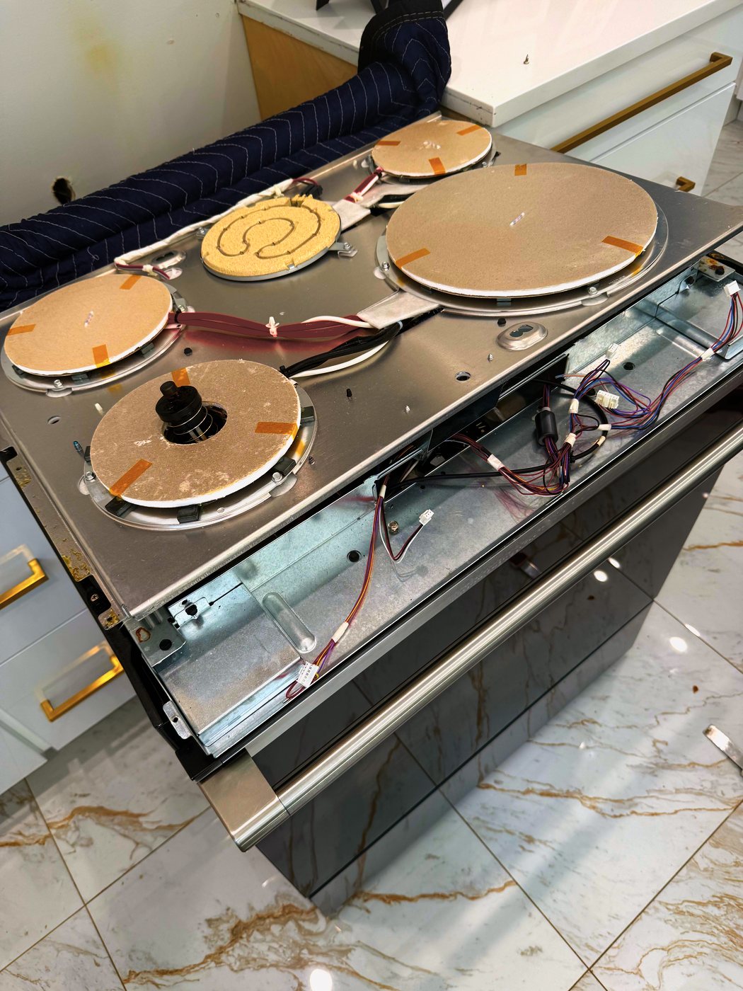 Cooktop lifted: four induction coils, wiring intact, nothing scorched. The fault was not out here