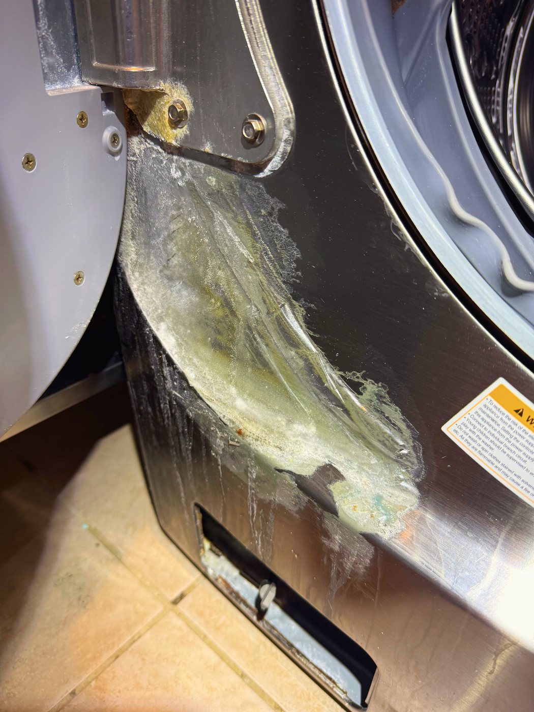 The door panel. The finish has been eaten through and is lifting away in sheets — this is what the cleaning did to steel