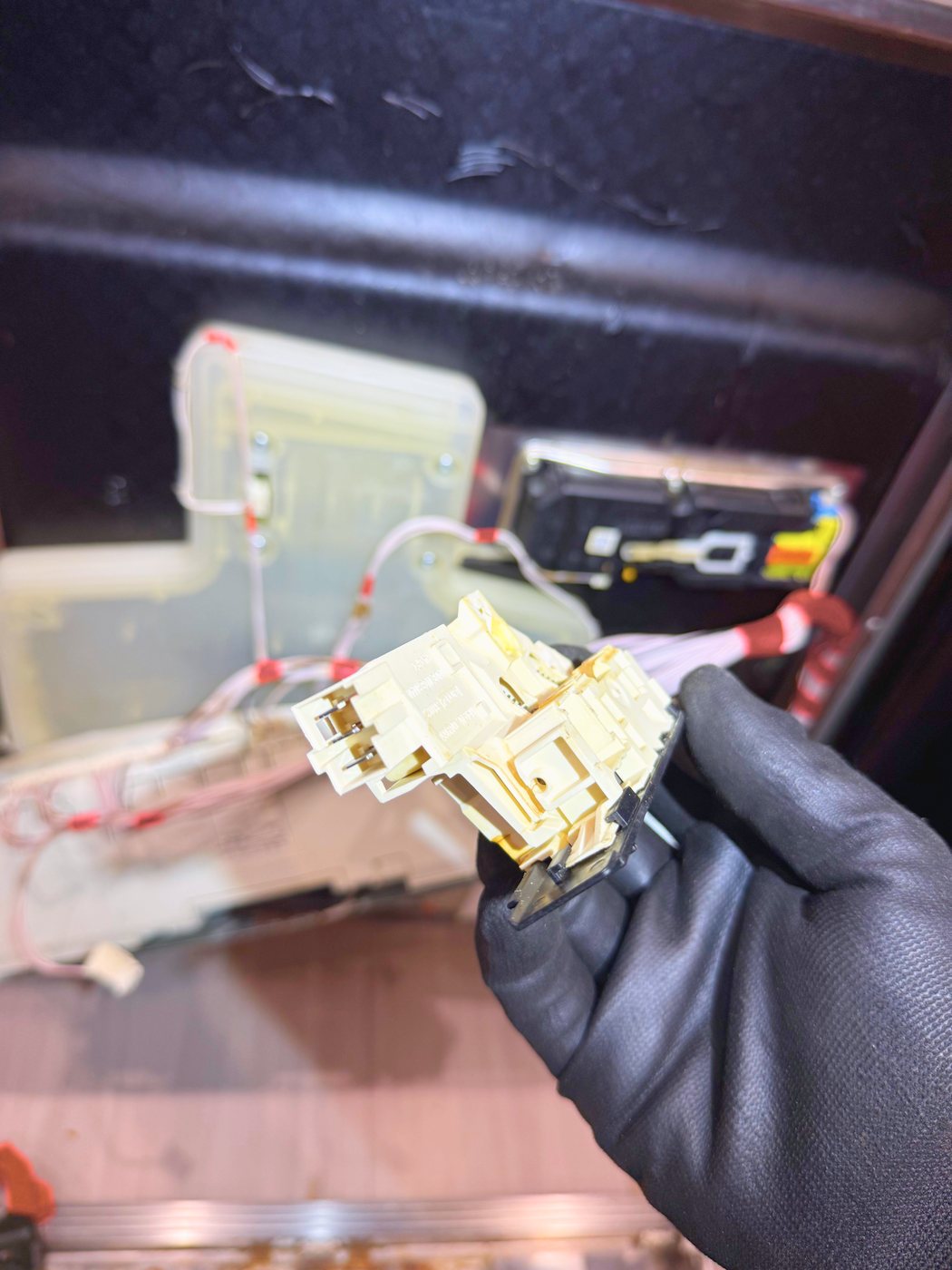 The old door lock assembly out of the machine. The catch inside it no longer travelled far enough to close the contact