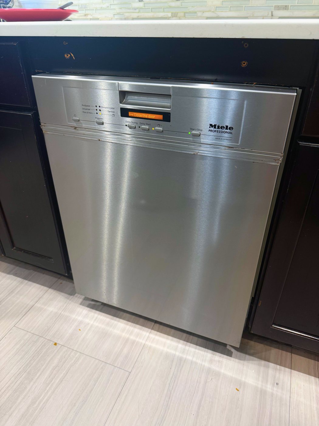 The Miele Professional dishwasher this repair was done on, with the door shut and the display asking for it to be closed