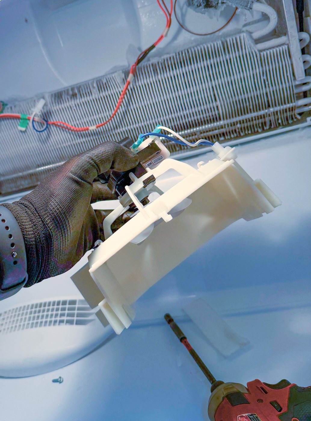 The evaporator fan motor assembly out of the machine, with the coil behind it. This one fan feeds both compartments