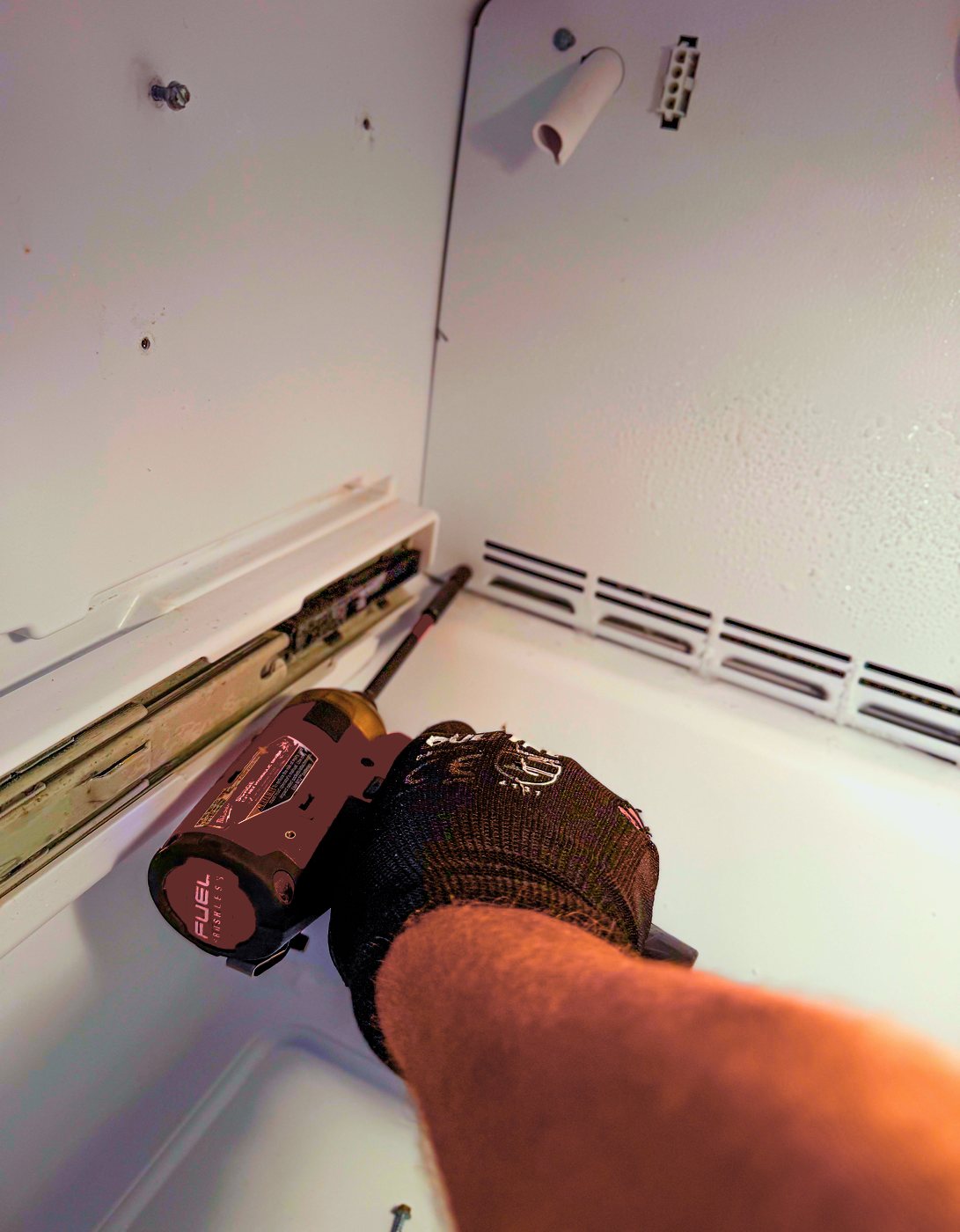 Taking out the drawer rails to reach the rear panel — the only way to see the coil and the fan instead of guessing at them